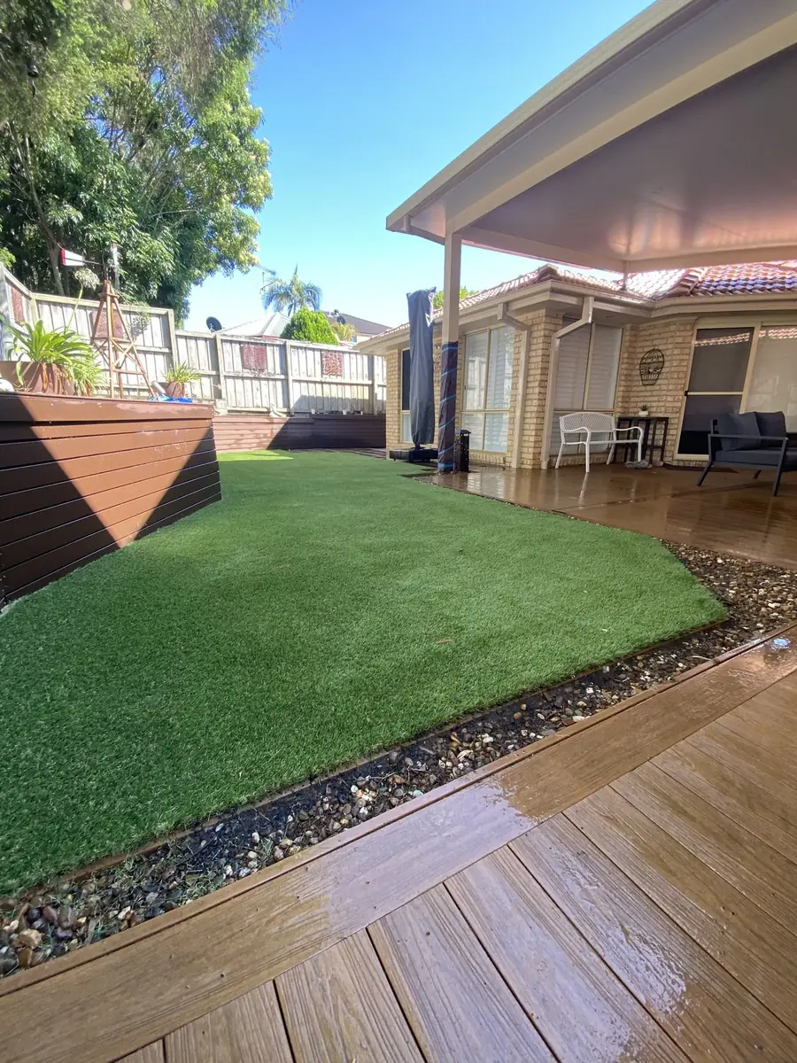 Artificial lawn meeting a timber deck after rain