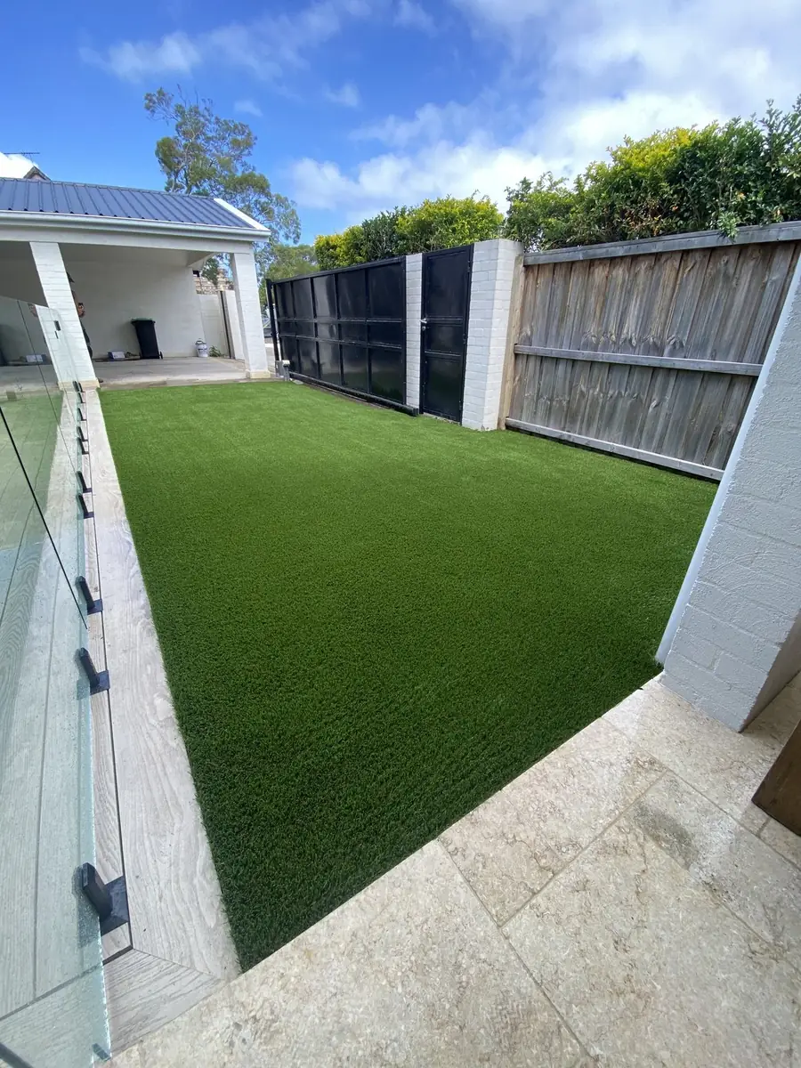 Narrow lawn between a glass pool fence and a timber fence