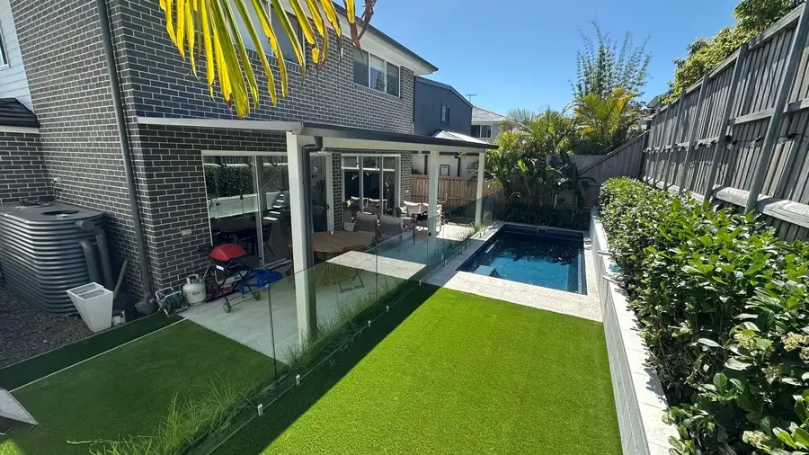 Artificial lawn between a pool fence and hedge in a Sydney backyard